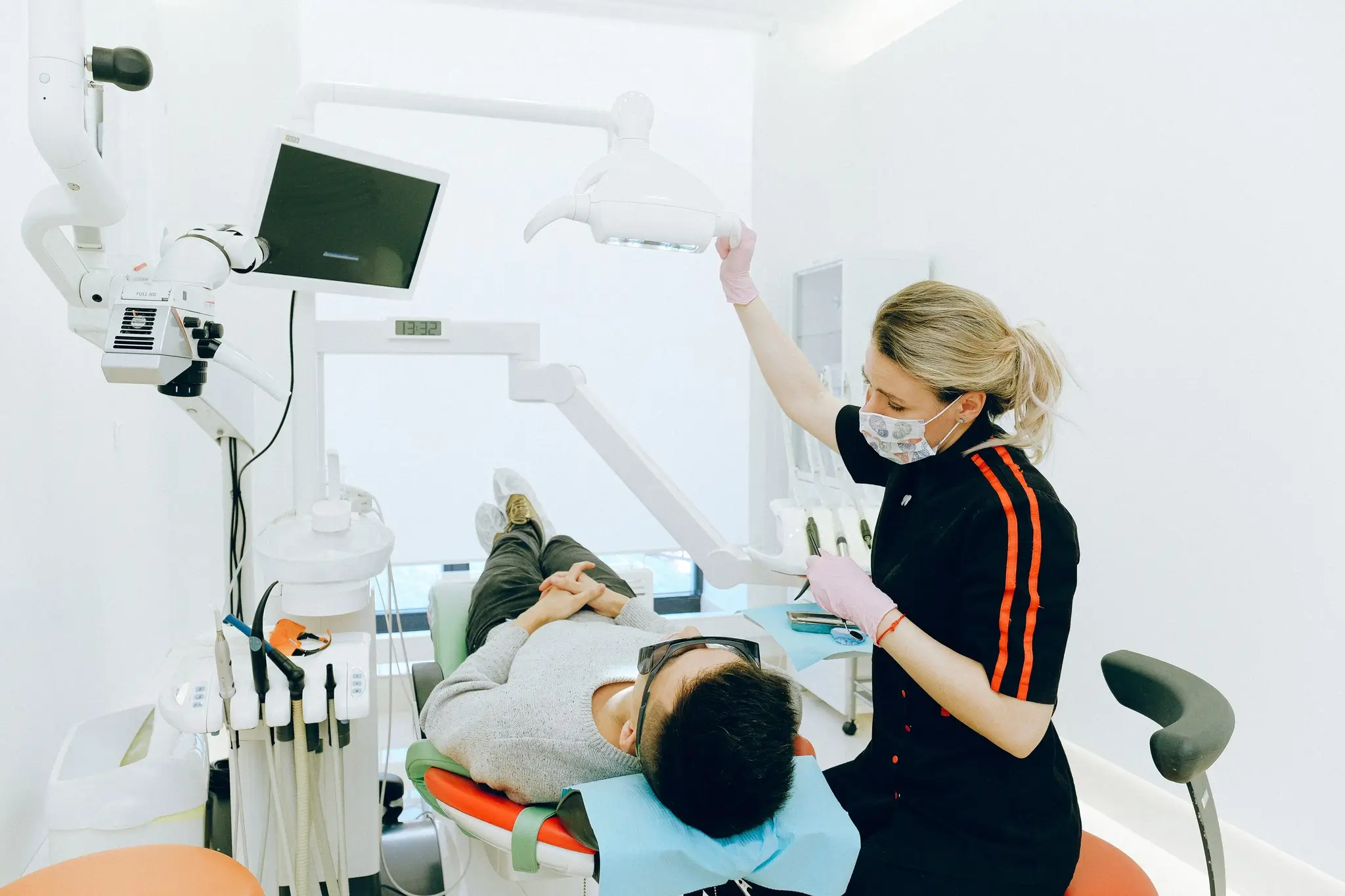 Dentist adjusting overhead light above patient in modern clinic